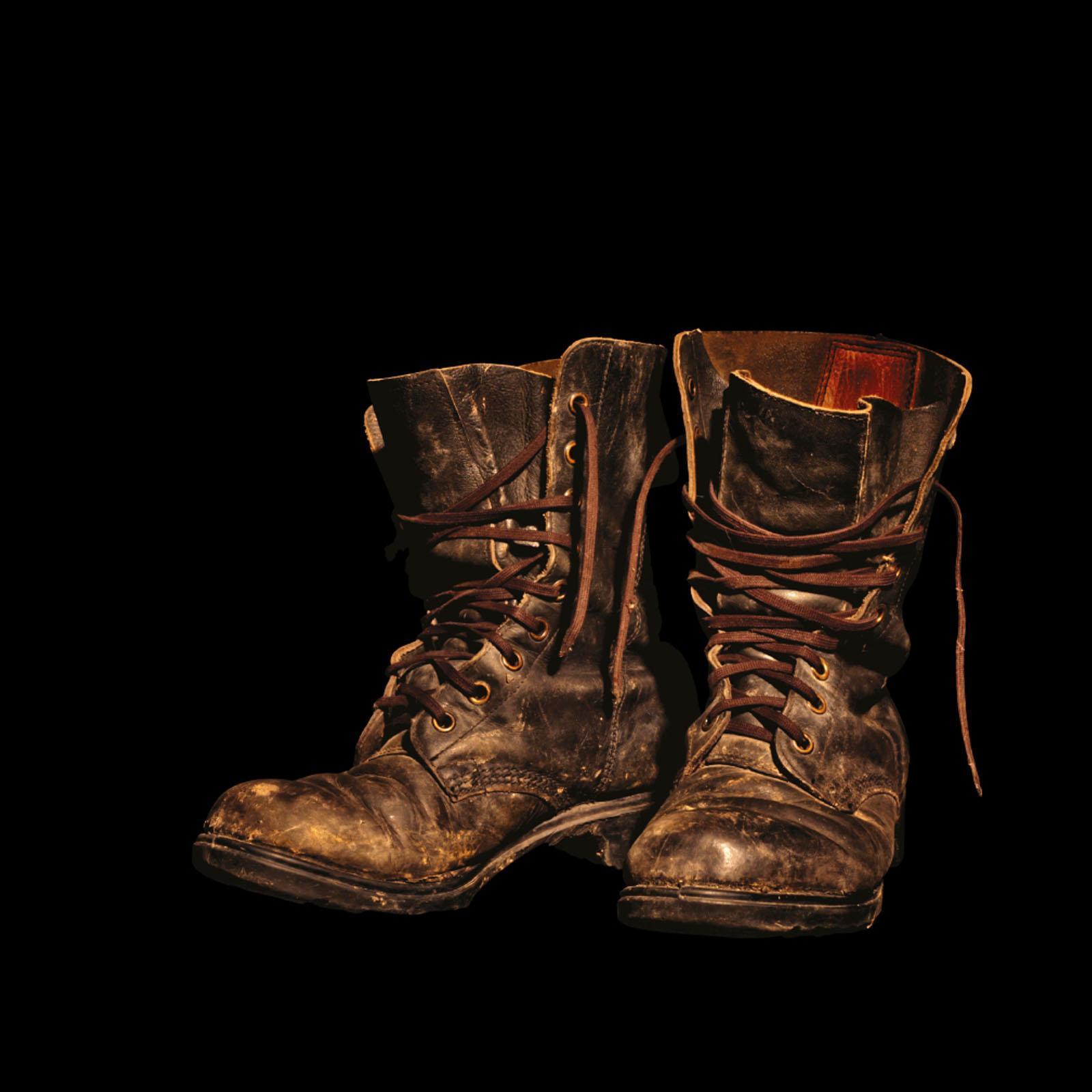 Worn brown boots against a black background